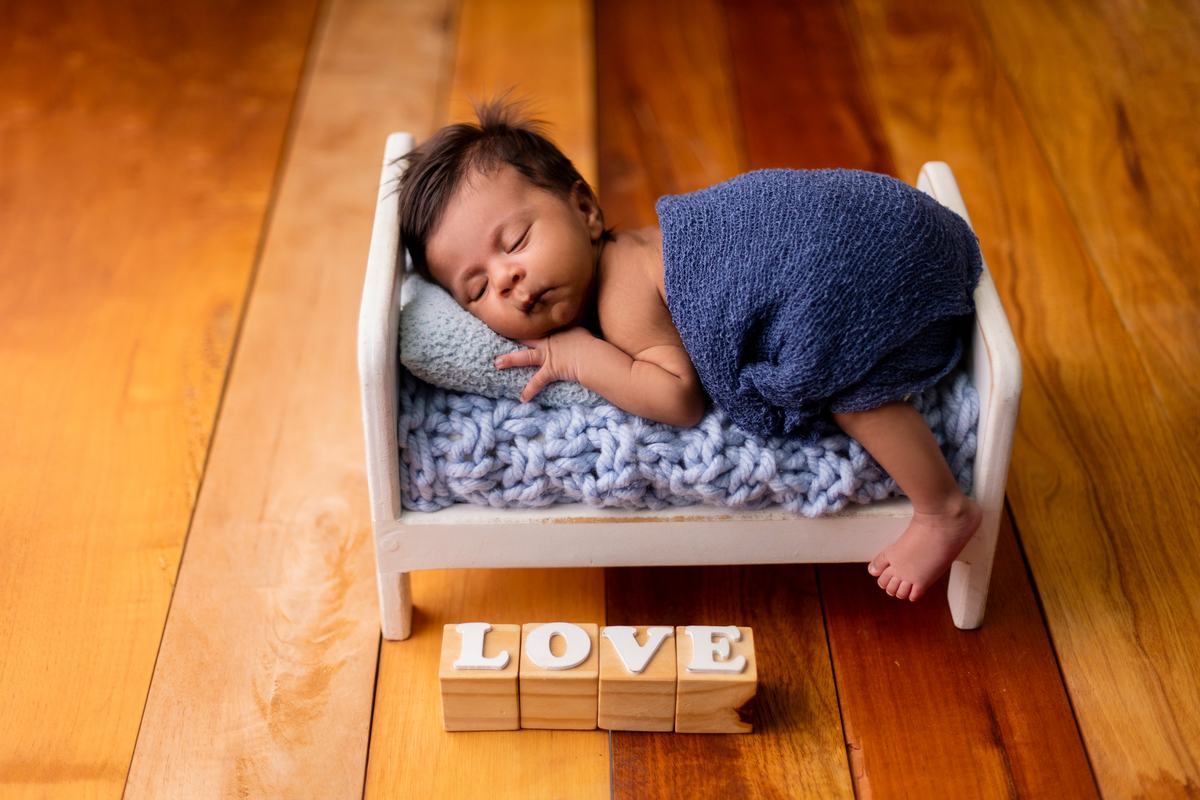 newborn de bruços na props cama