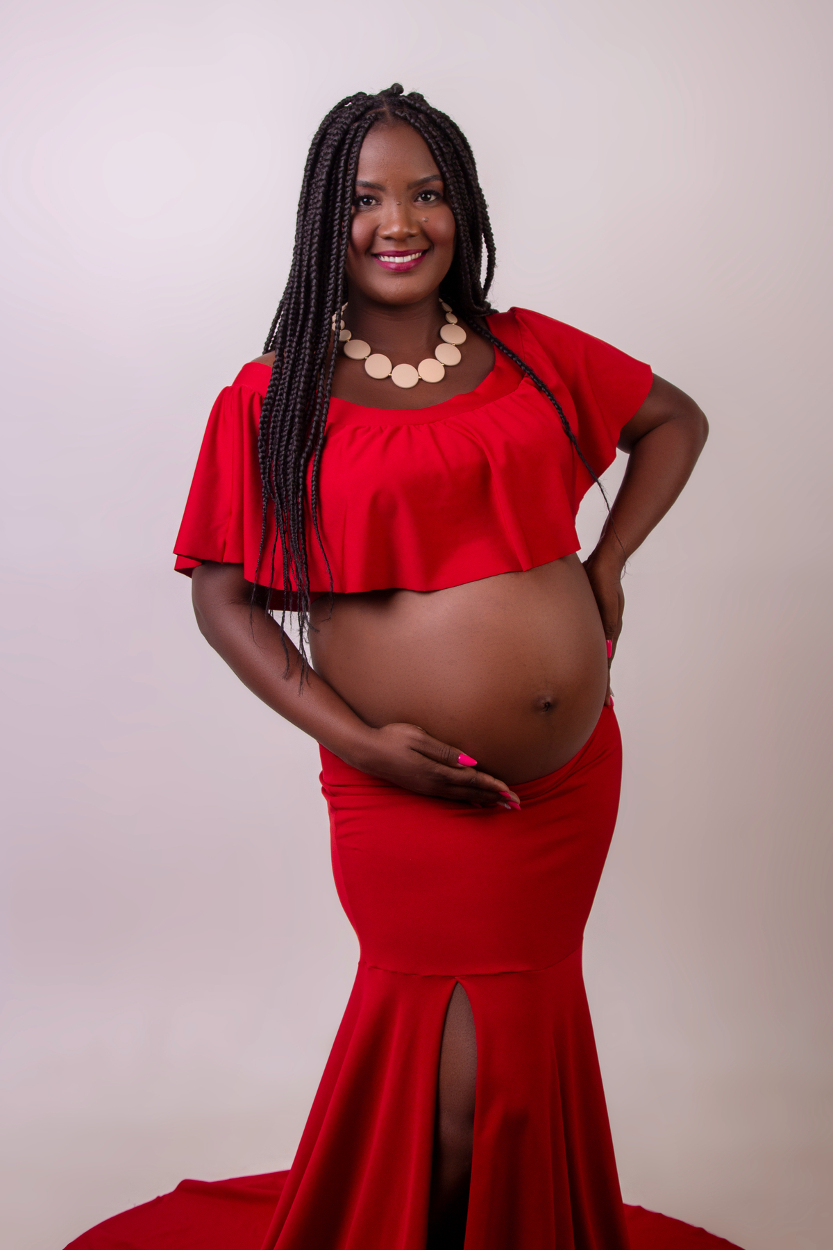 gestante com conjunto vermelho com mão na cintura e outra na barriga