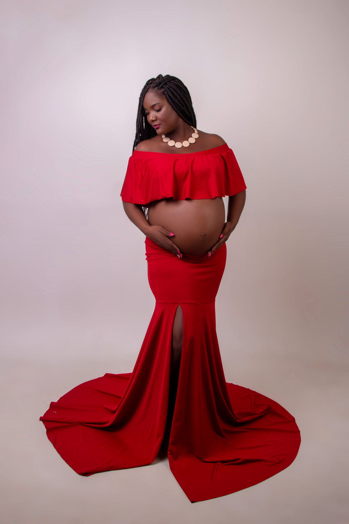 gestante com conjunto vermelho com mãos na barriga