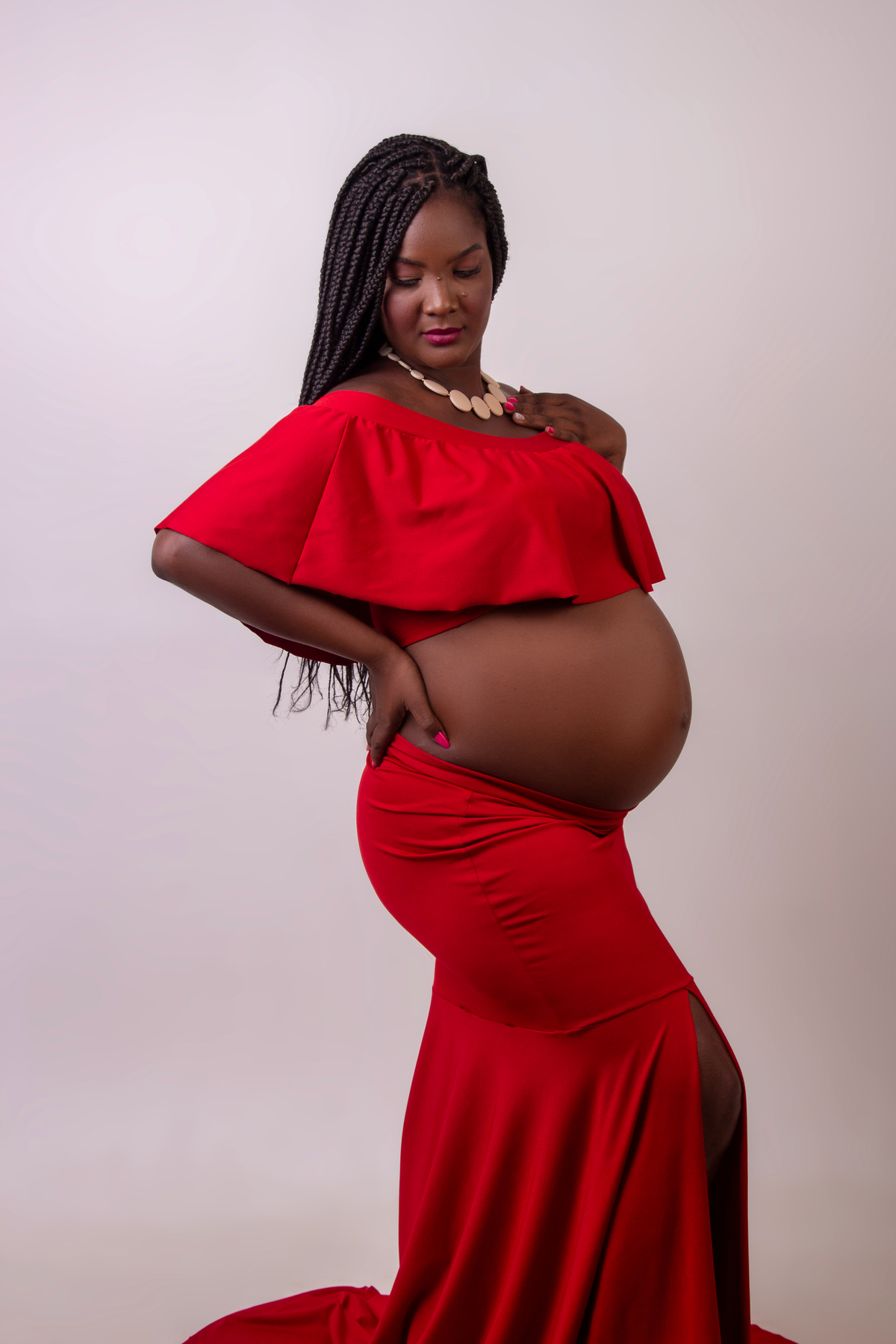 gestante com conjunto vermelho com mão na cintura e outra no colar