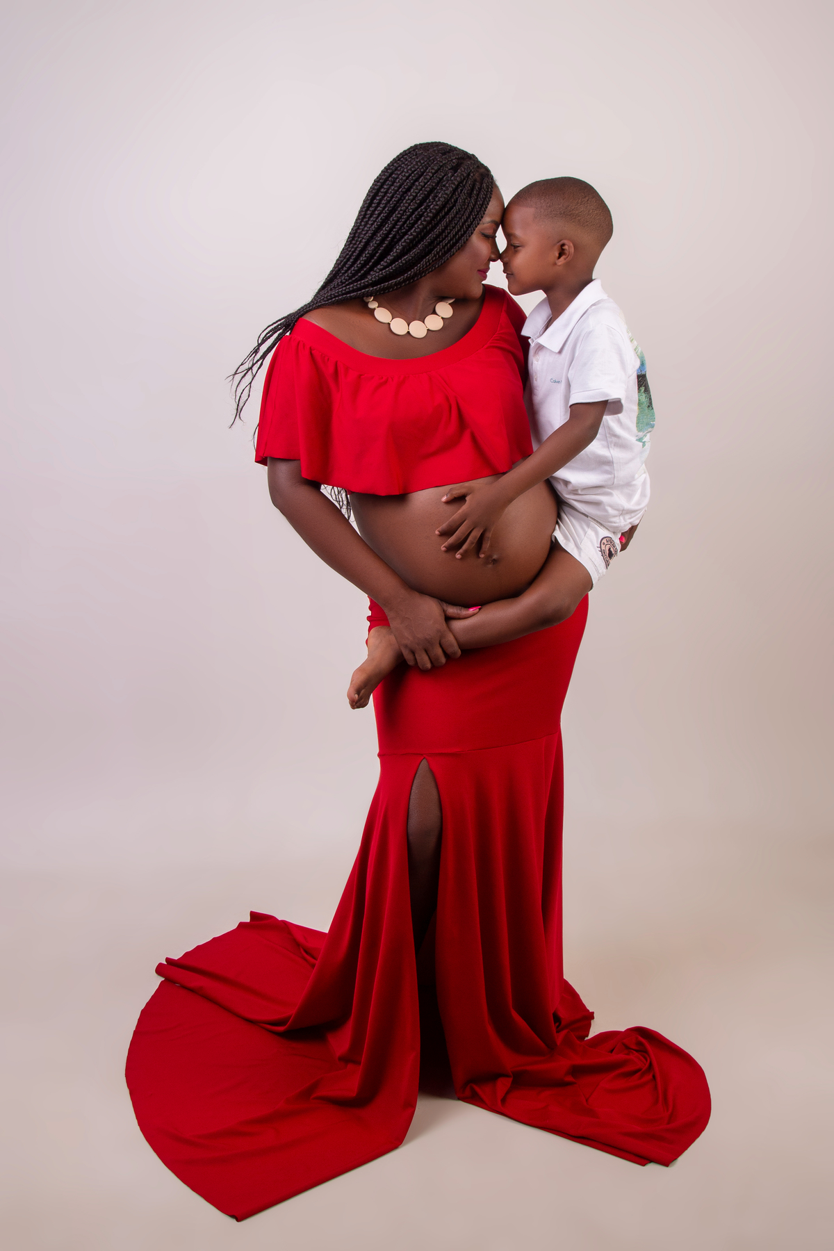 gestante com conjunto vermelho carregando seu filho na cintura