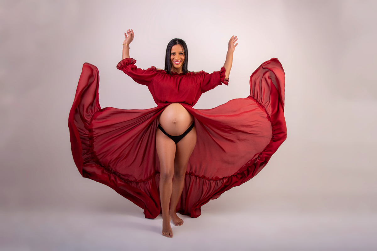 gestante com vestido longo vermelho no ar