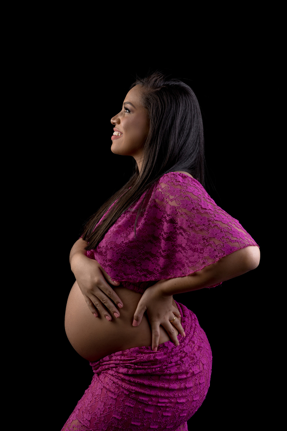 gestante com conjunto roxo com mão na cintura e outra na barriga