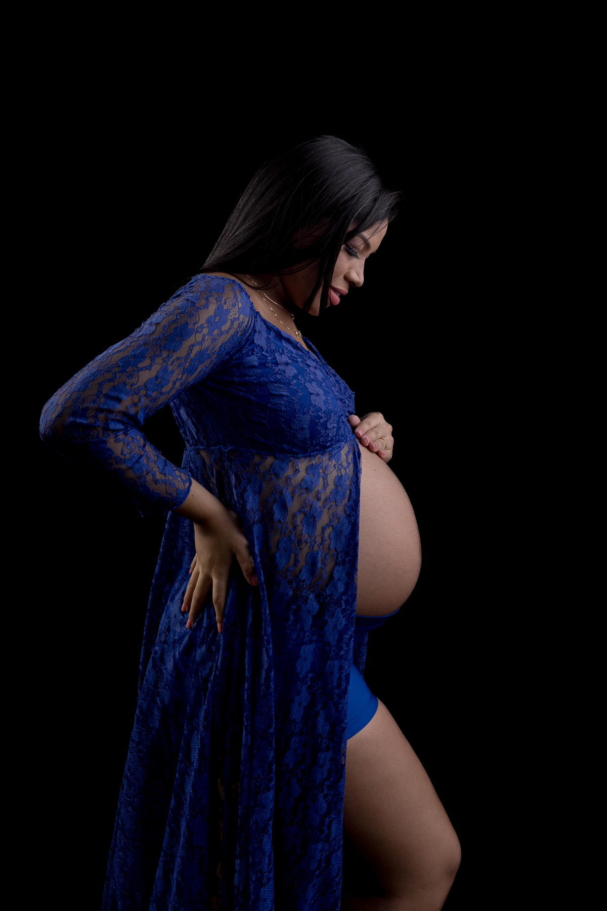 gestante com vestido azul com mão na cintura e outra na barriga