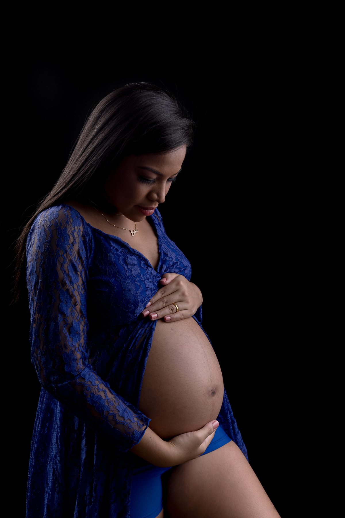 gestante com vestido azul abraçando a barriga