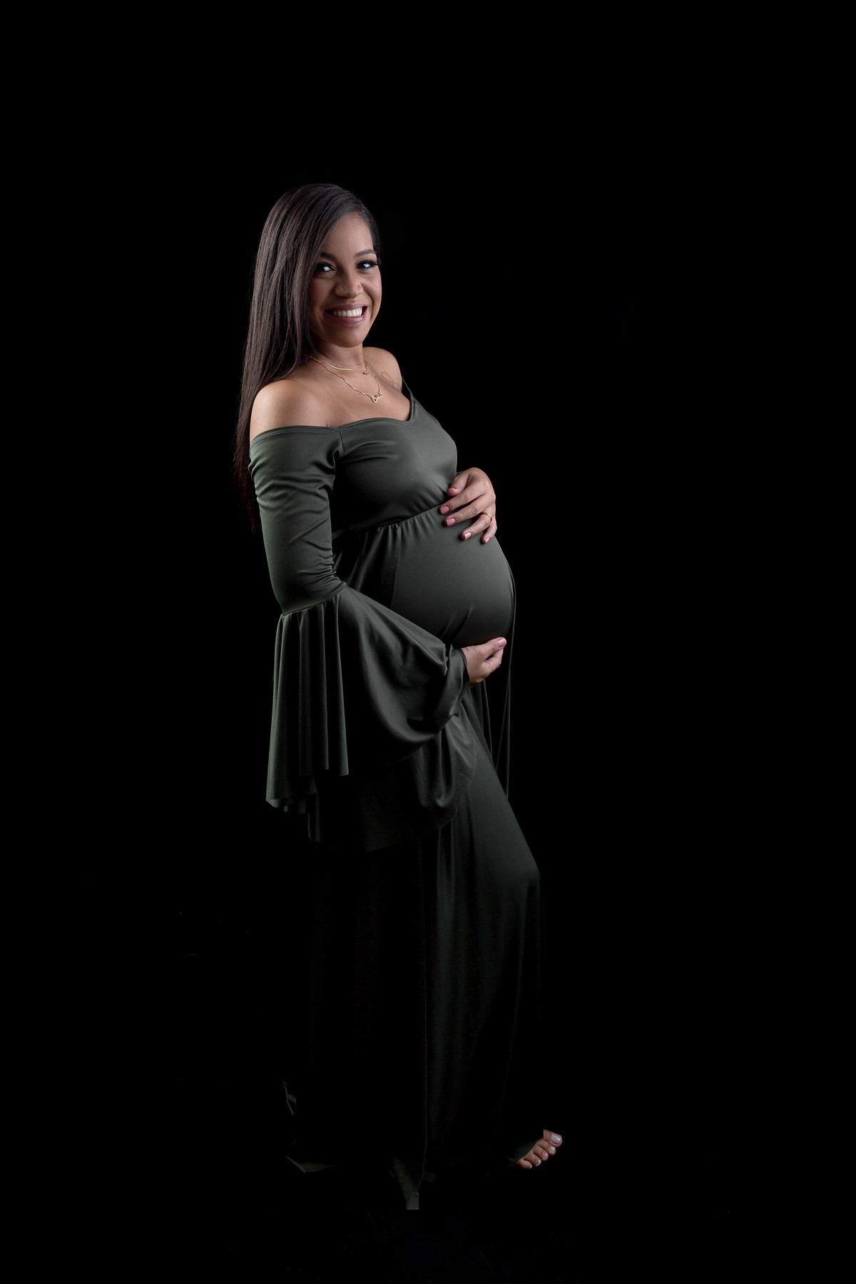 gestante com vestido verde abraçando a barriga