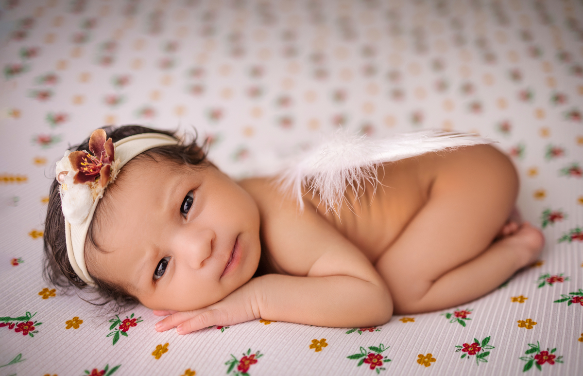 newborn de bruços com asas de anjo e tiara