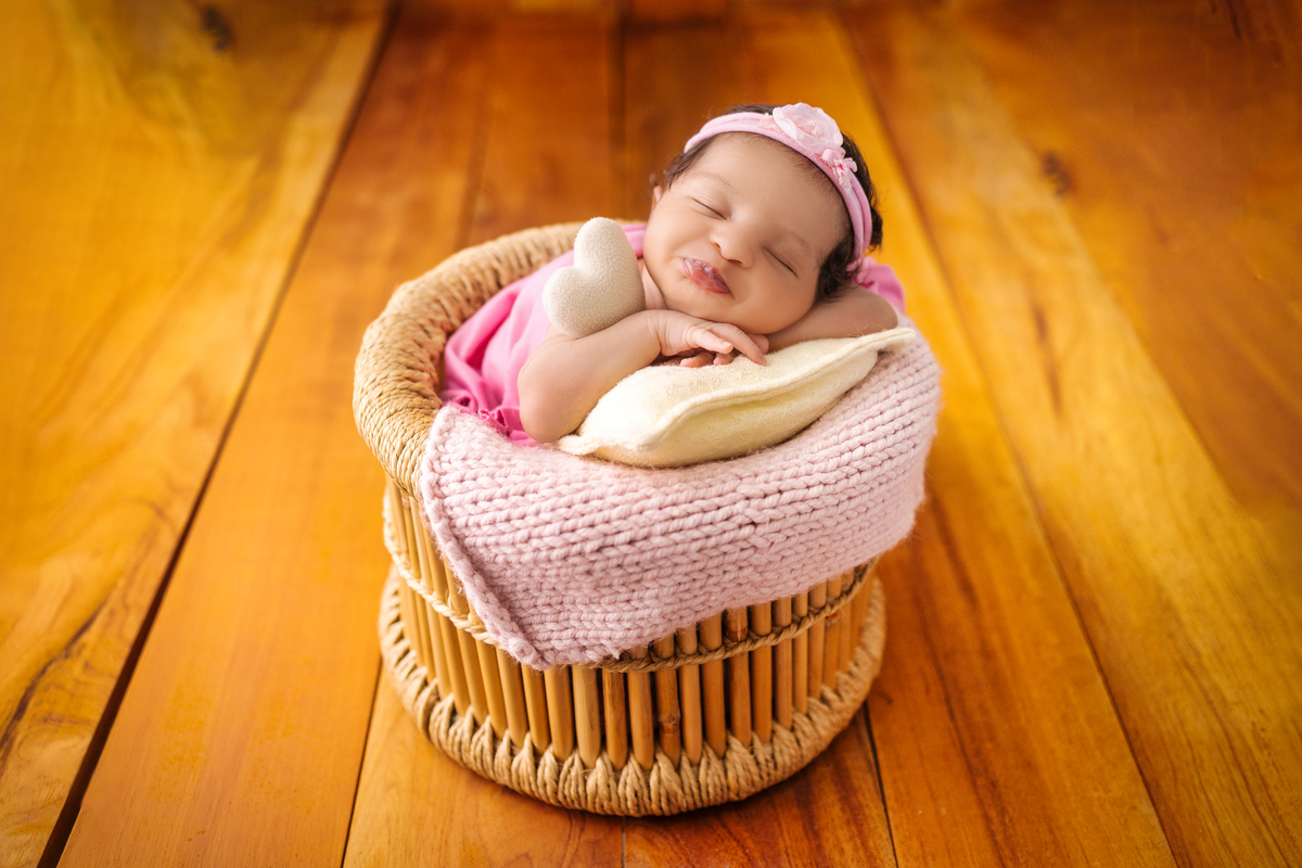 newborn coberto no balde com tiara e coração