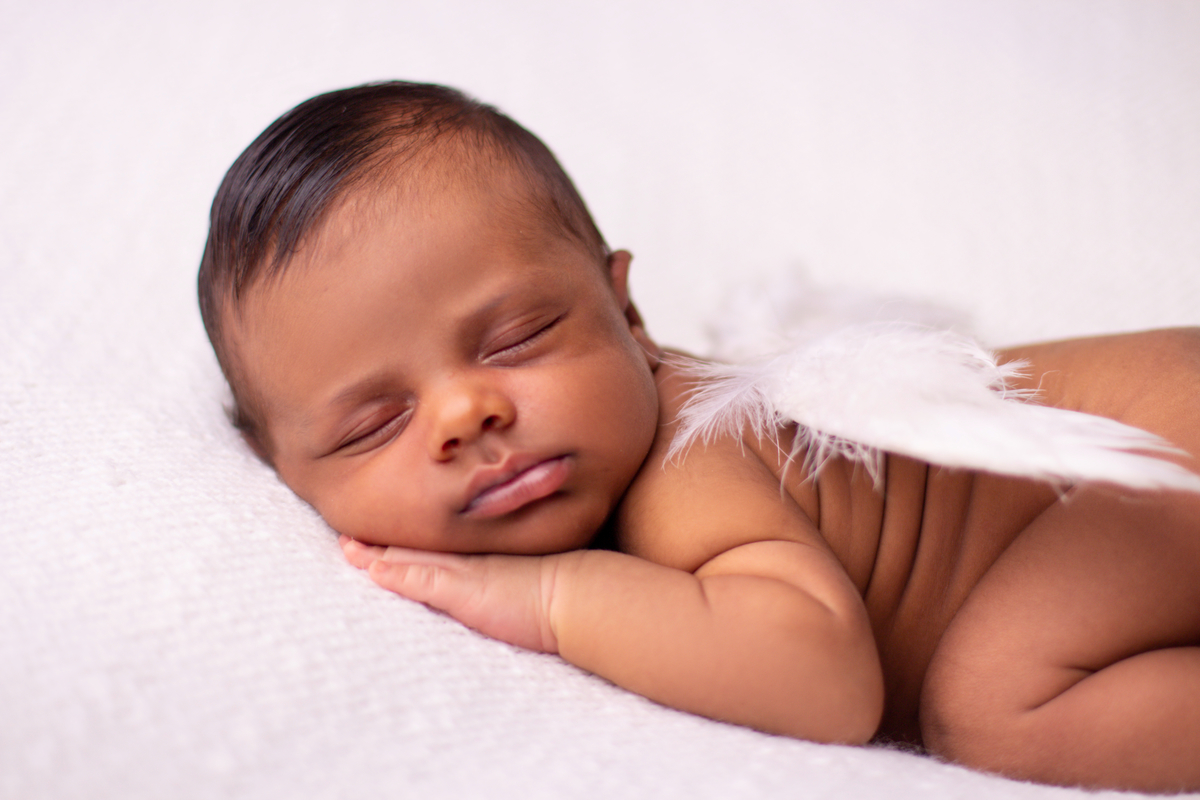 newborn de bruços com asas de anjo