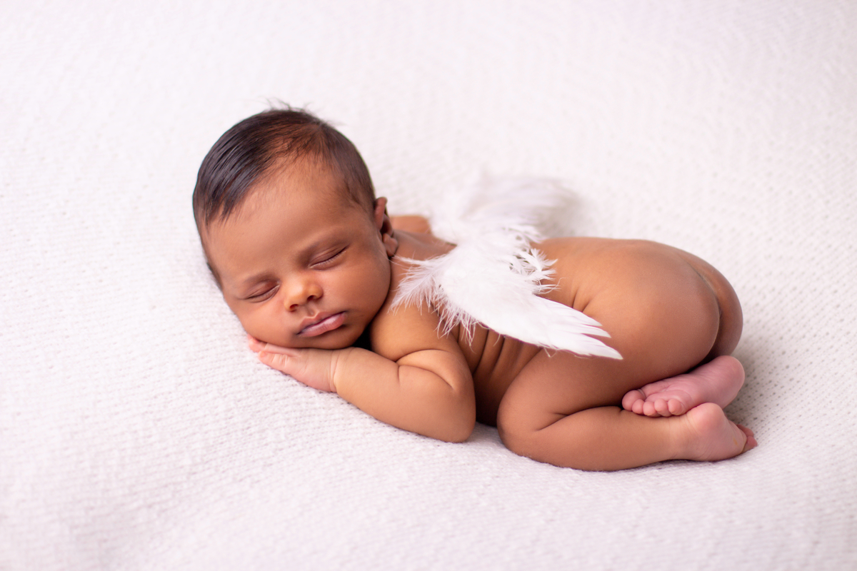 newborn de bruços com asas de anjo