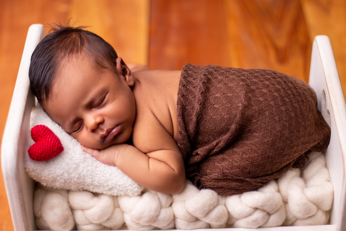 newborn de bruços na props cama e coração