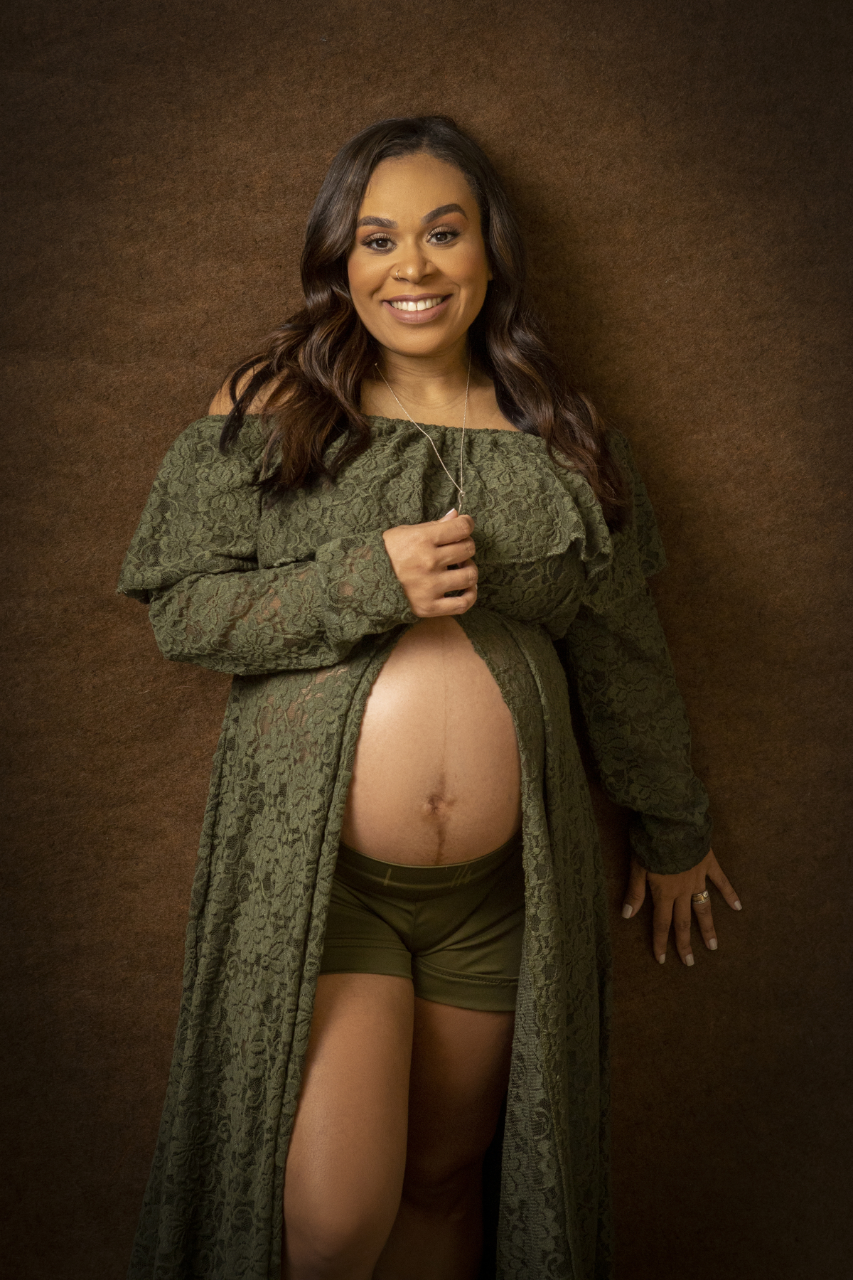 gestante encostada na parede e segurando o colar