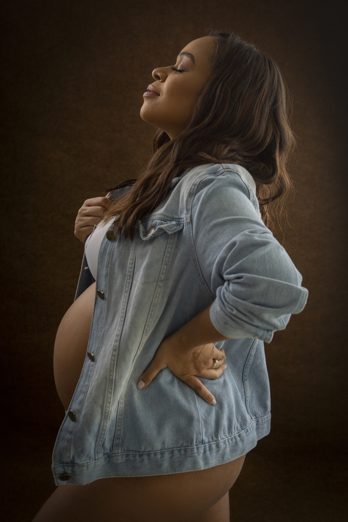 gestante com a mão na jaqueta e outra na cintura