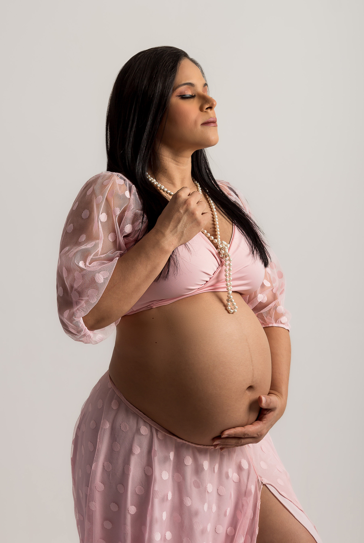 gestante com a mão na barriga e outra segurando colar