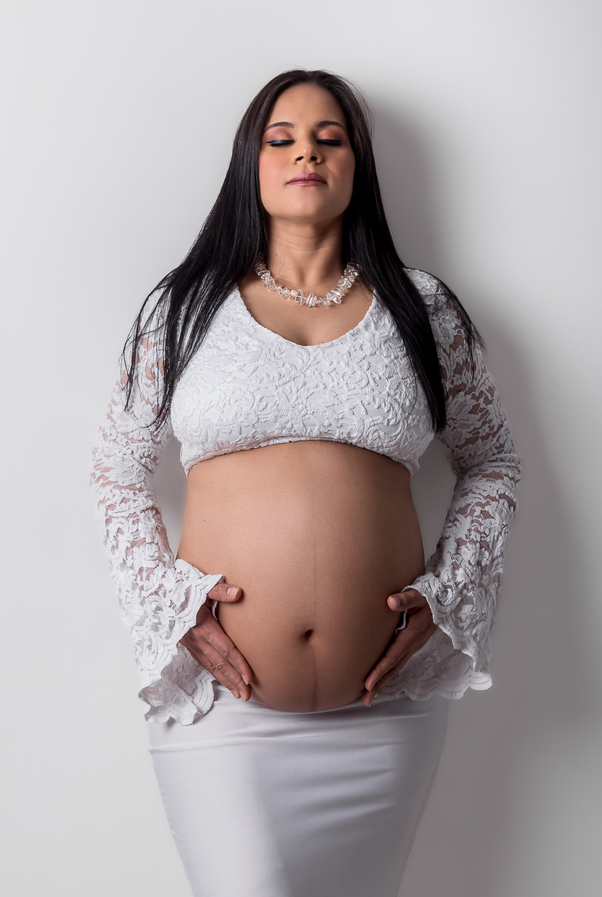 gestante encostada na parede com as mãos na barriga