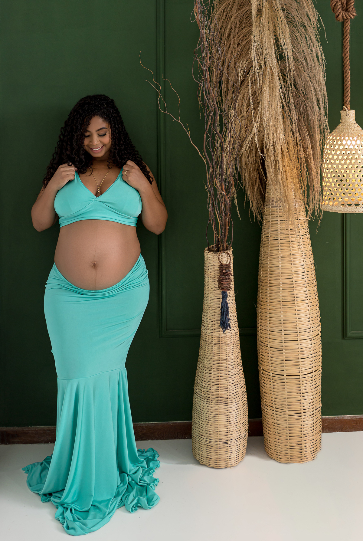 gestante apoiada na parede e vendo a barriga