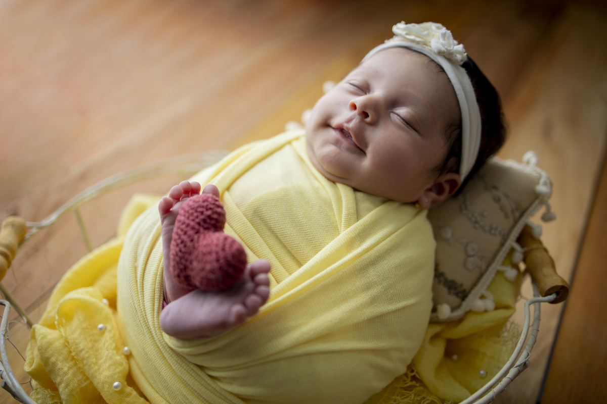 wrap newborn amarelo e props cesta segurando coração