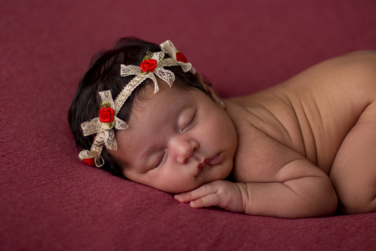 newborn de bruços com tiara de flores