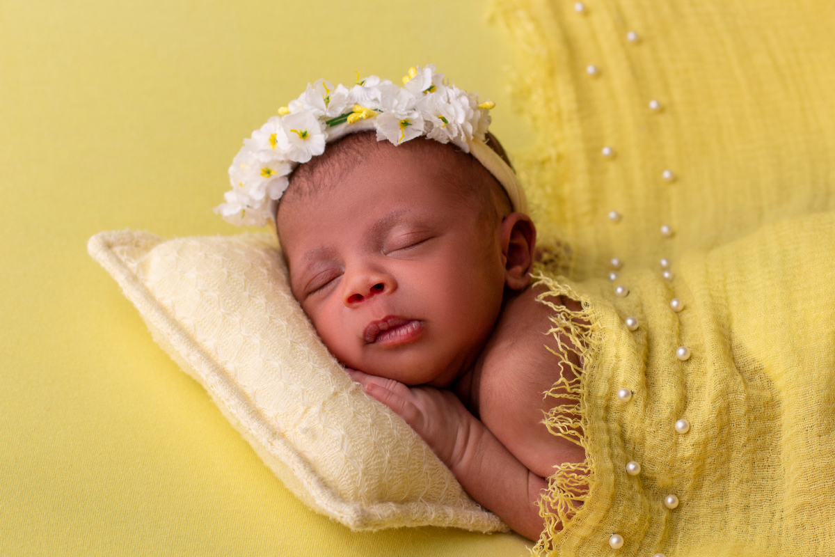 newborn deitado de bruços com tiara de flores