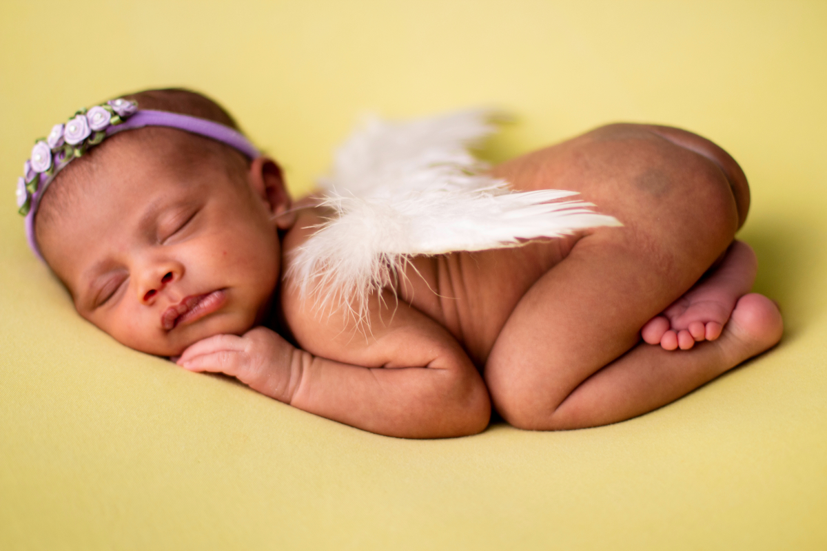 newborn deitado de bruços com asas de anjo