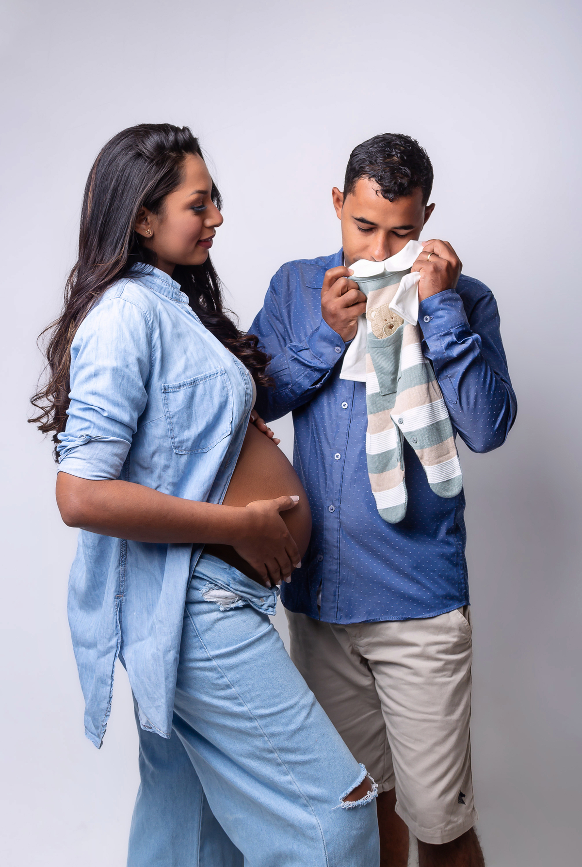 mamãe olhando papai cheirando roupinha do bebê