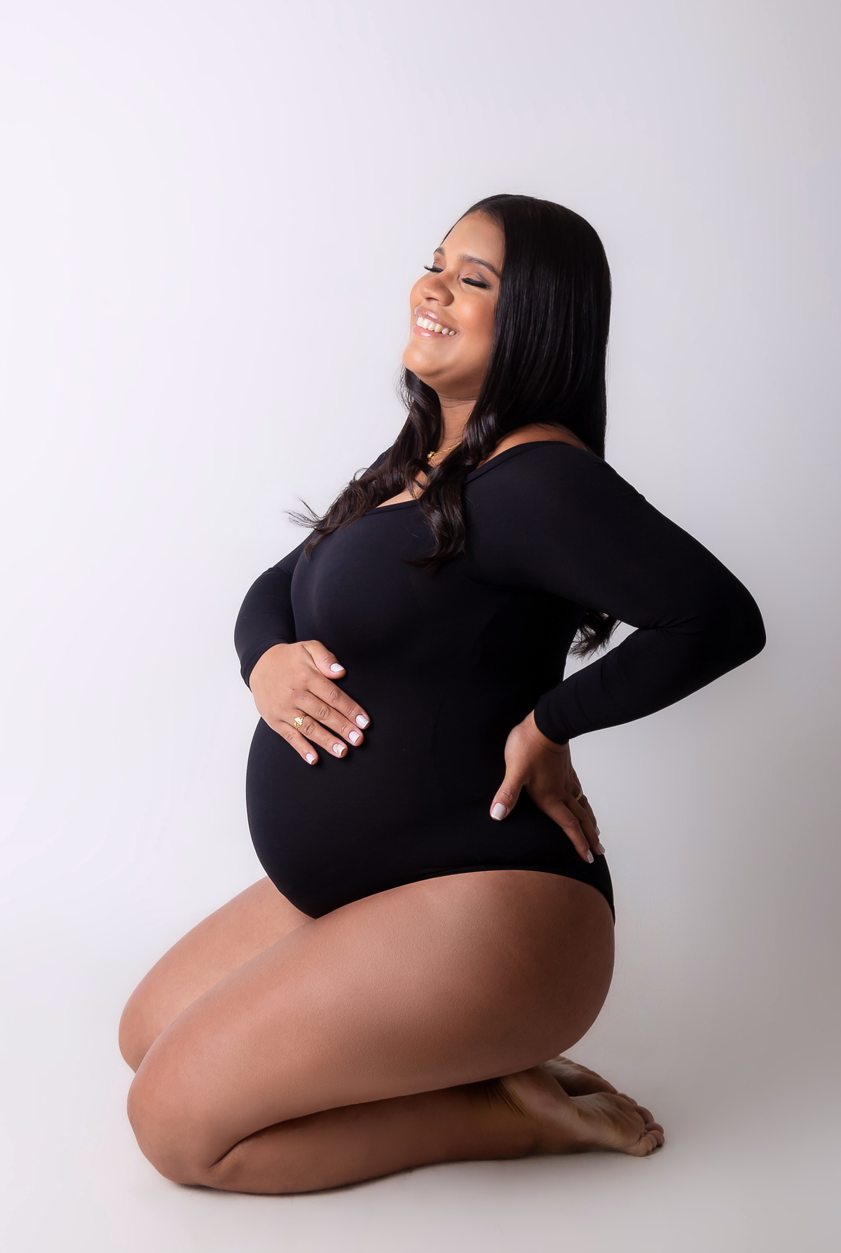 gestante de body com mão na cintura e outra na barriga