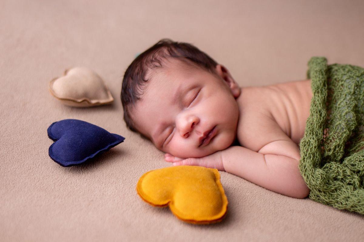 newborn de bruços com corações 