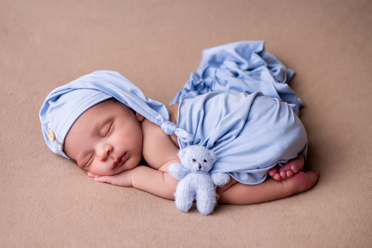newborn de bruços com gorro e ursinho