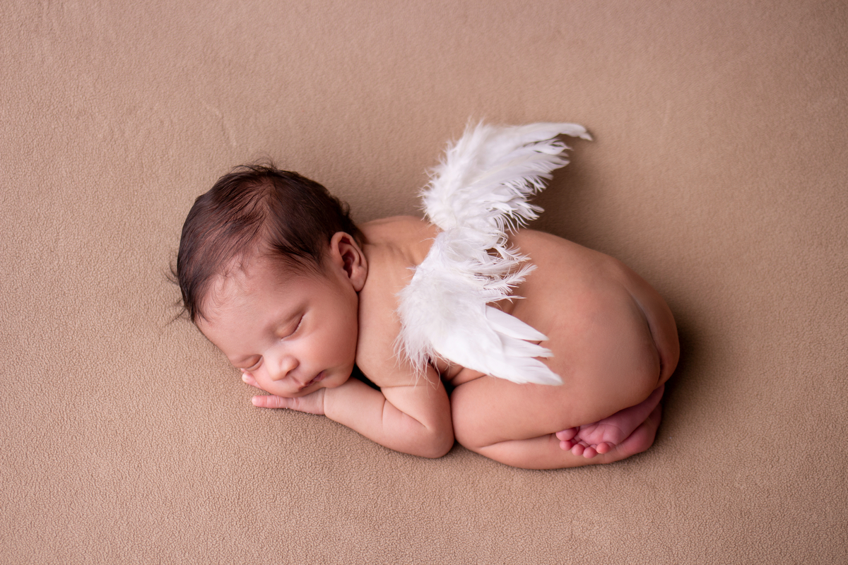 newborn de bruços com asas de anjos