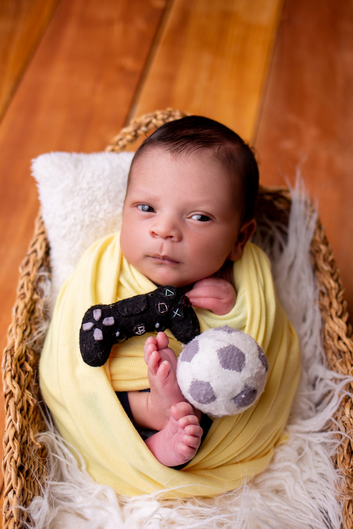 wrap newborn amarelo e props cesta segurando bola e controle game