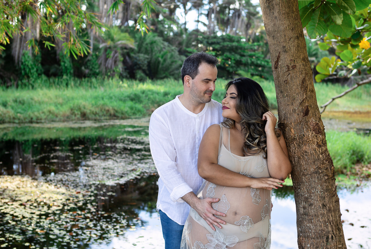 gestante encostada na árvore com seu marido