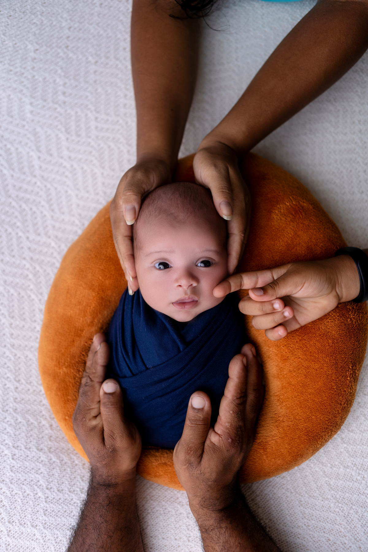 papai, mamãe e irmã tocando no recém nascido