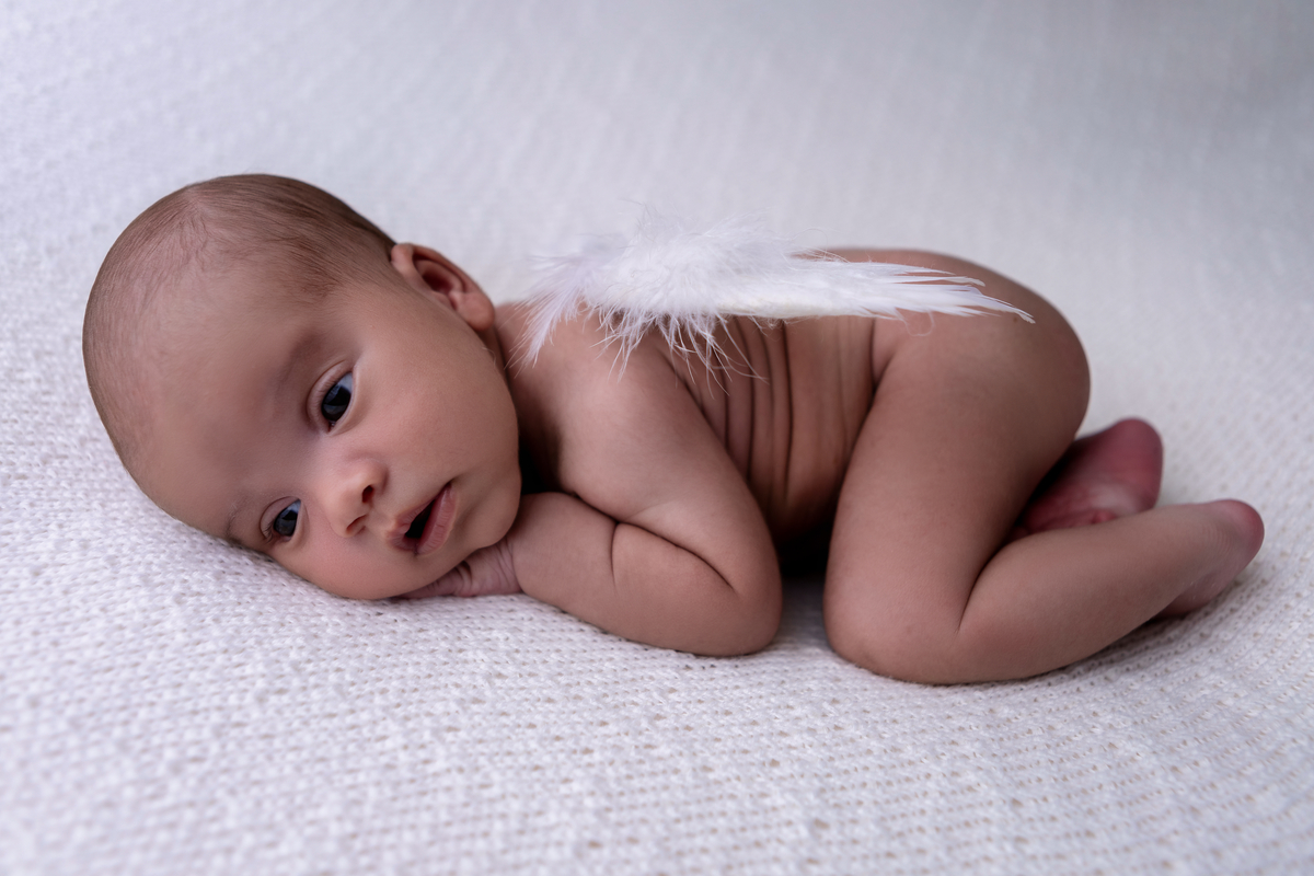 newborn de bruços com asas de anjos