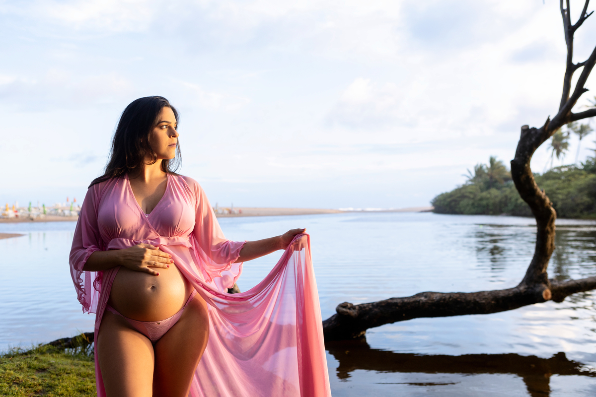 gestante segurando o vestido no lago 