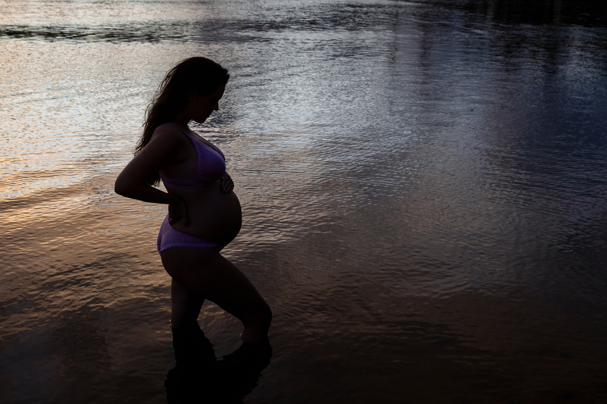 silhueta de gestante olhando pra barriga no lago