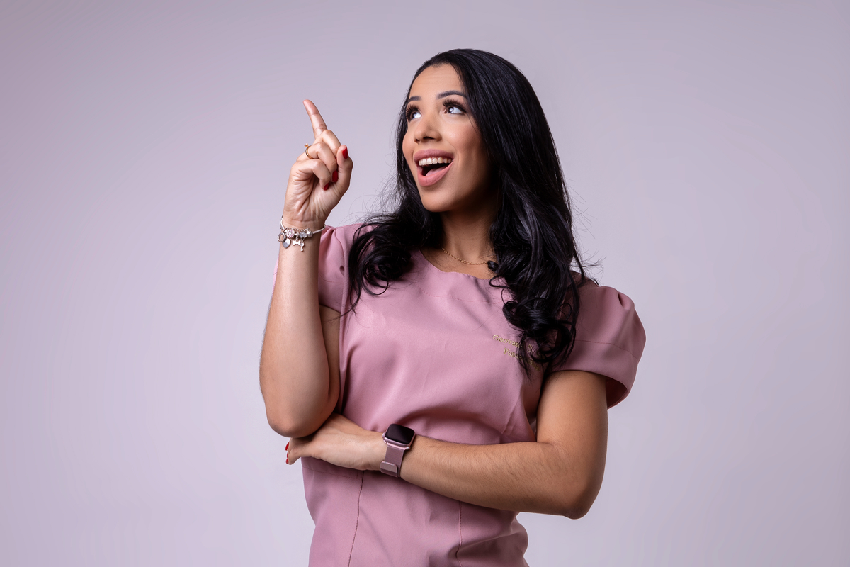 fonoaudióloga de braço cruzado apontando pra cima