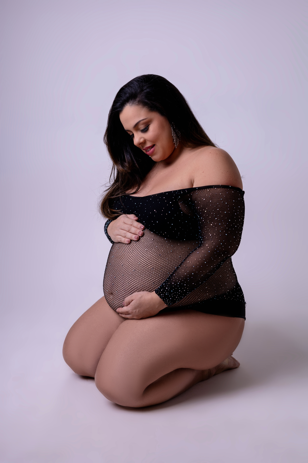 gestante ajoelhada abraçando a barriga