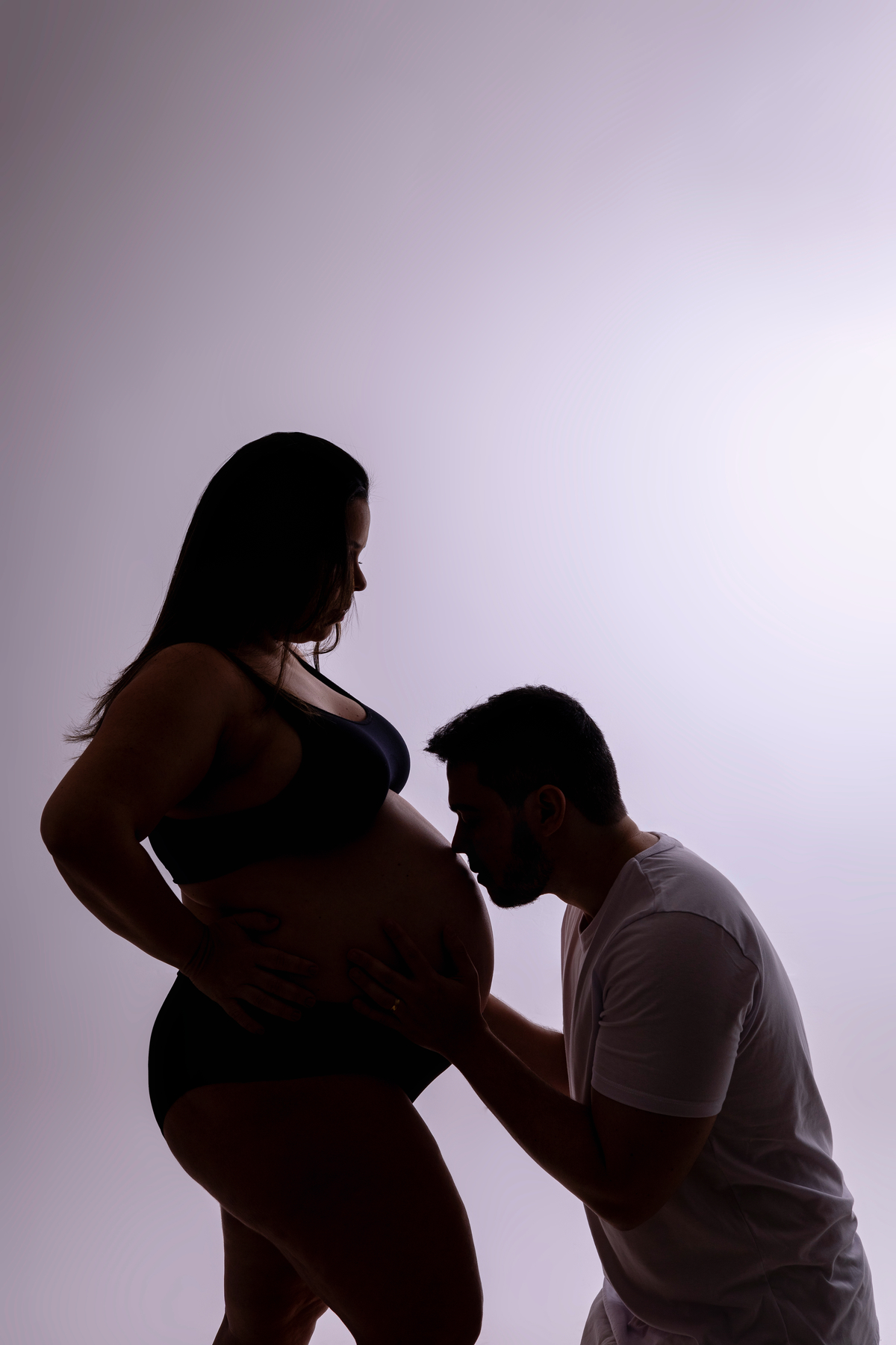 silhueta de papai beijando na barriga na gestante