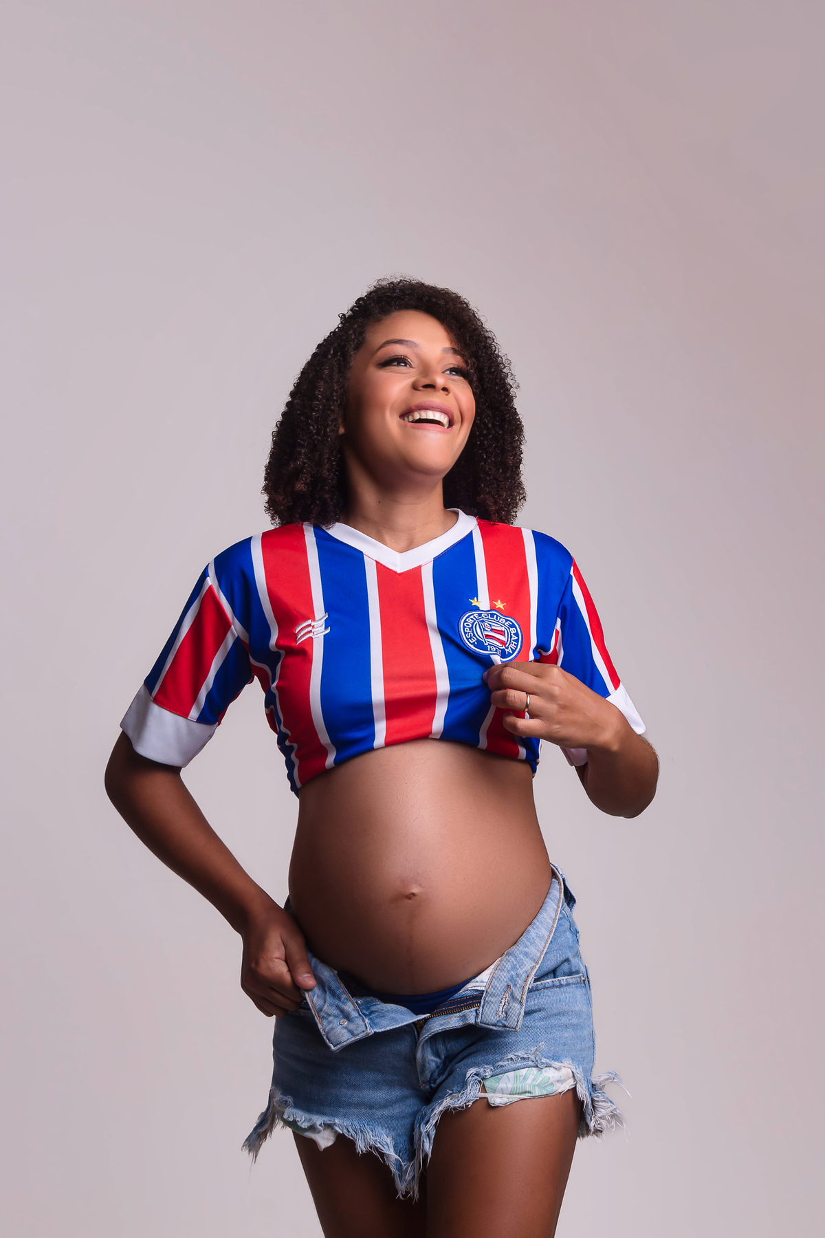 gestante segurando a alça da short e o escudo do time bahia