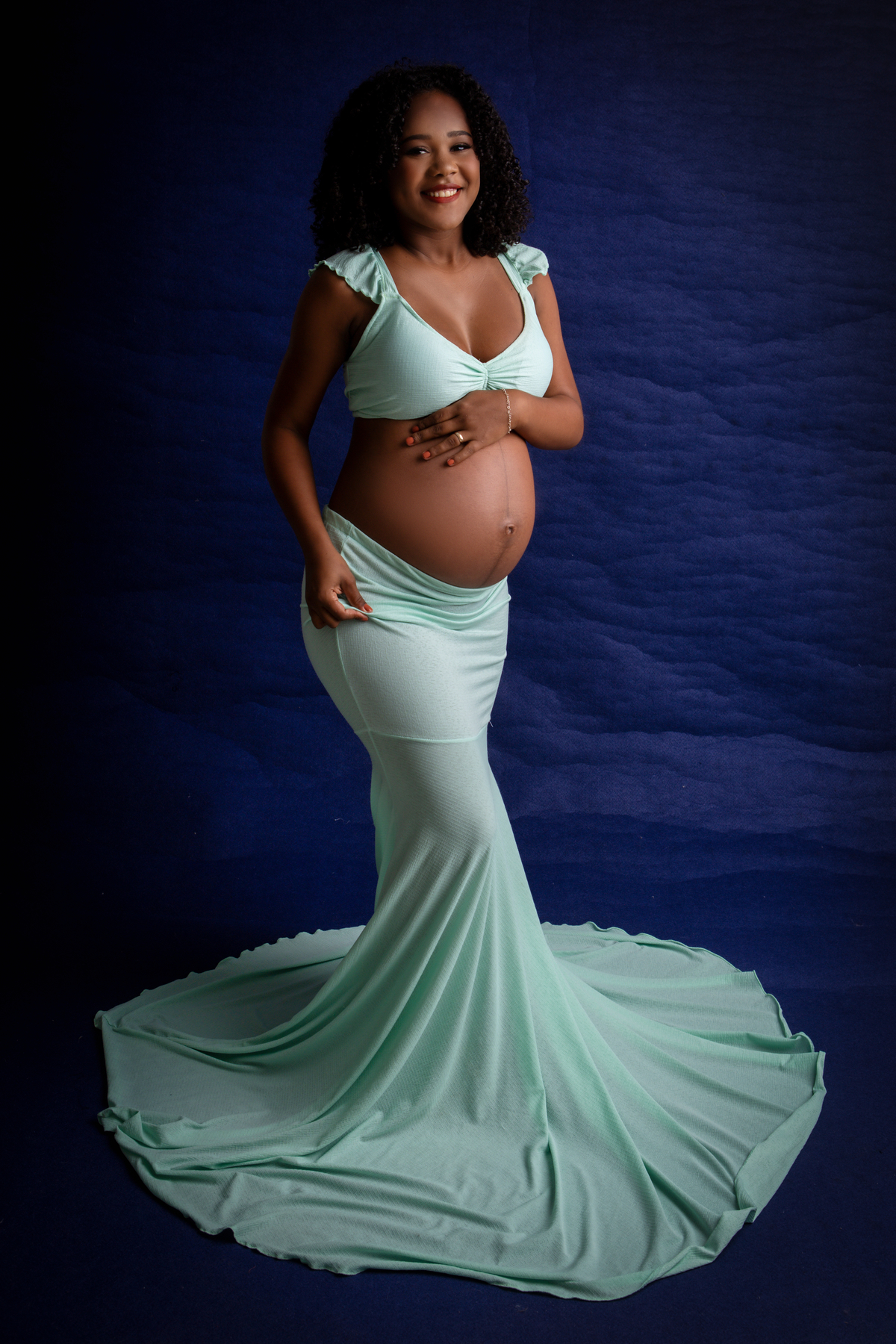 gestante com mão na barriga e outra segurando a saia