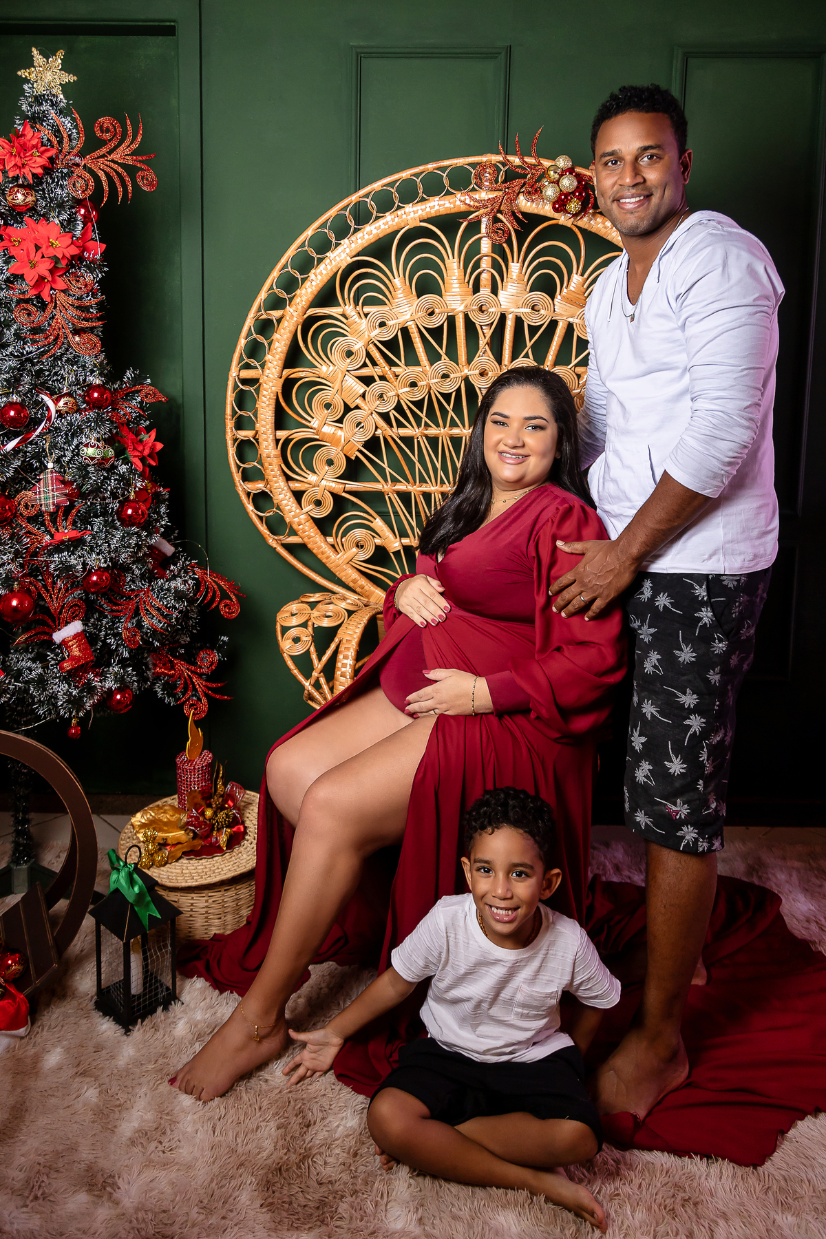 gestante sentada abraçando a barriga com seu marido e filho