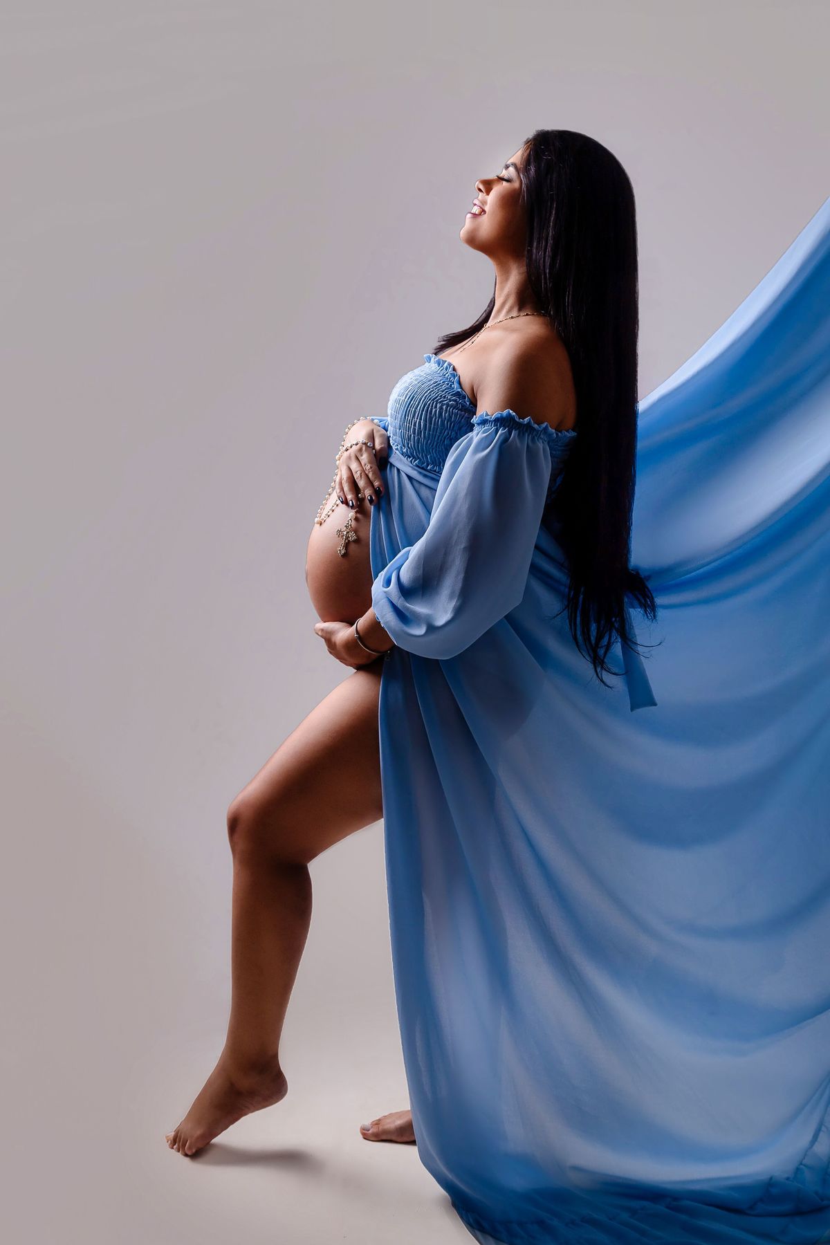 gestante abraçando a barriga segurando o terço