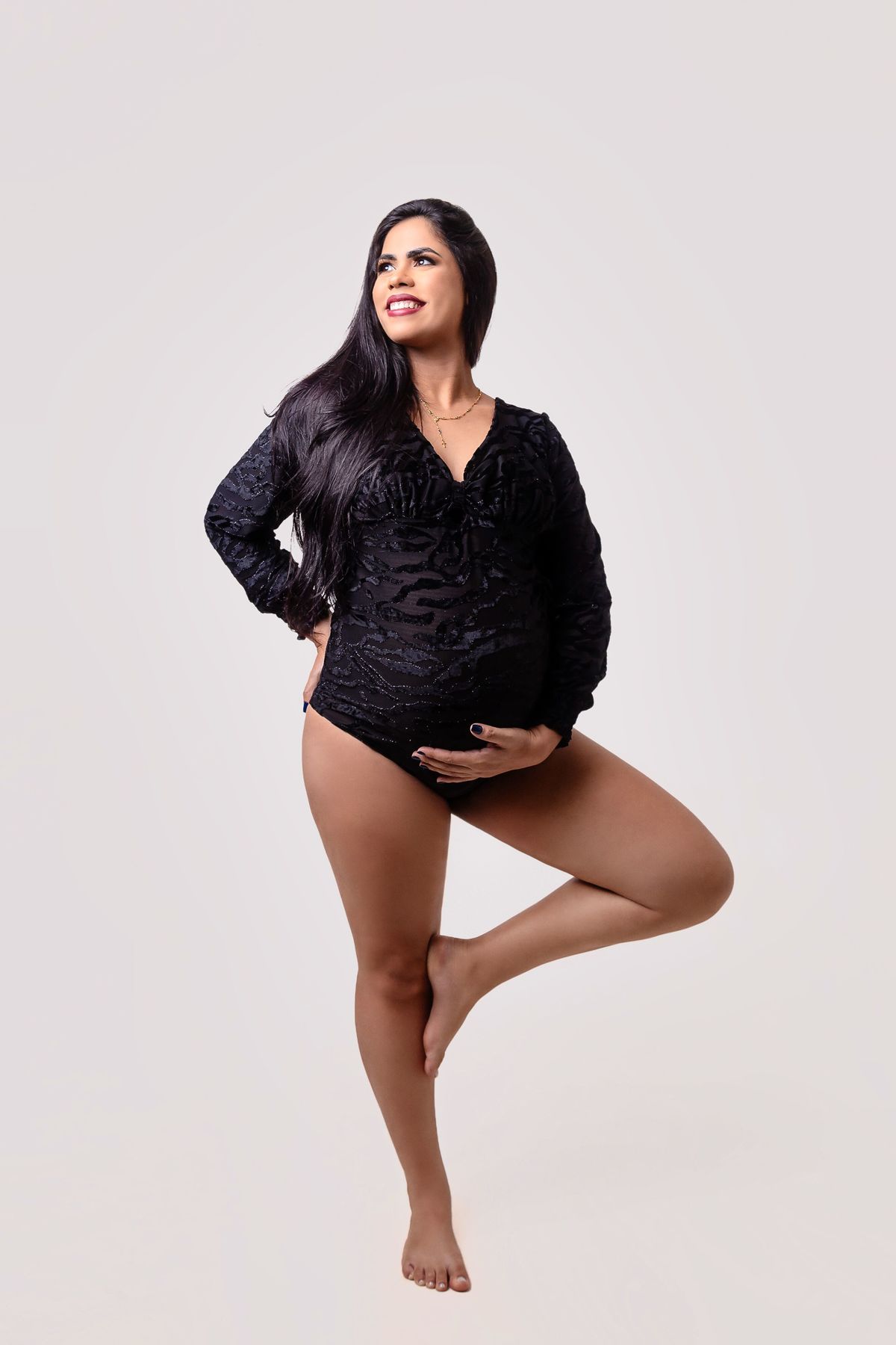 gestante com a perna formando o 4, segurando a barriga e outra na cintura