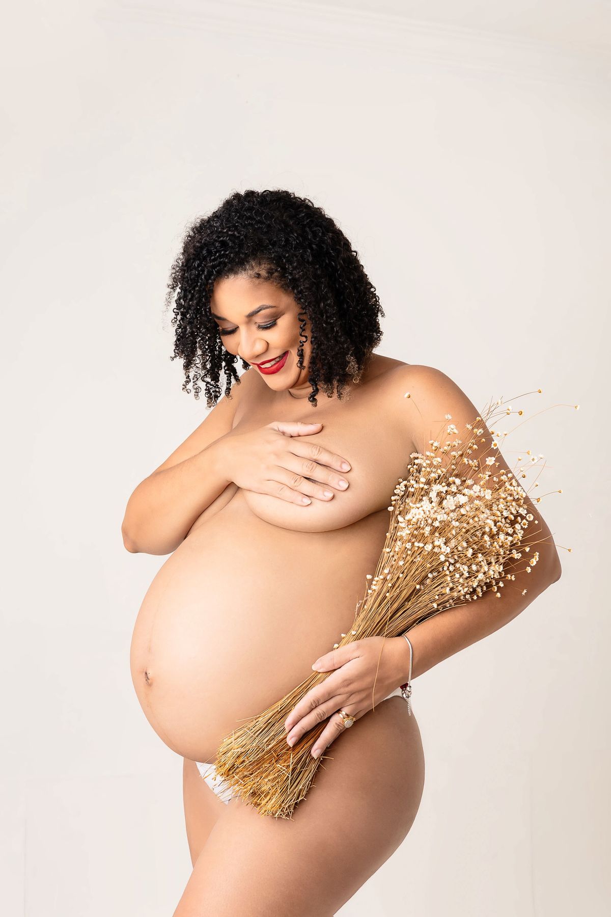 gestante seminua olhando pra barriga com buquê de trigo