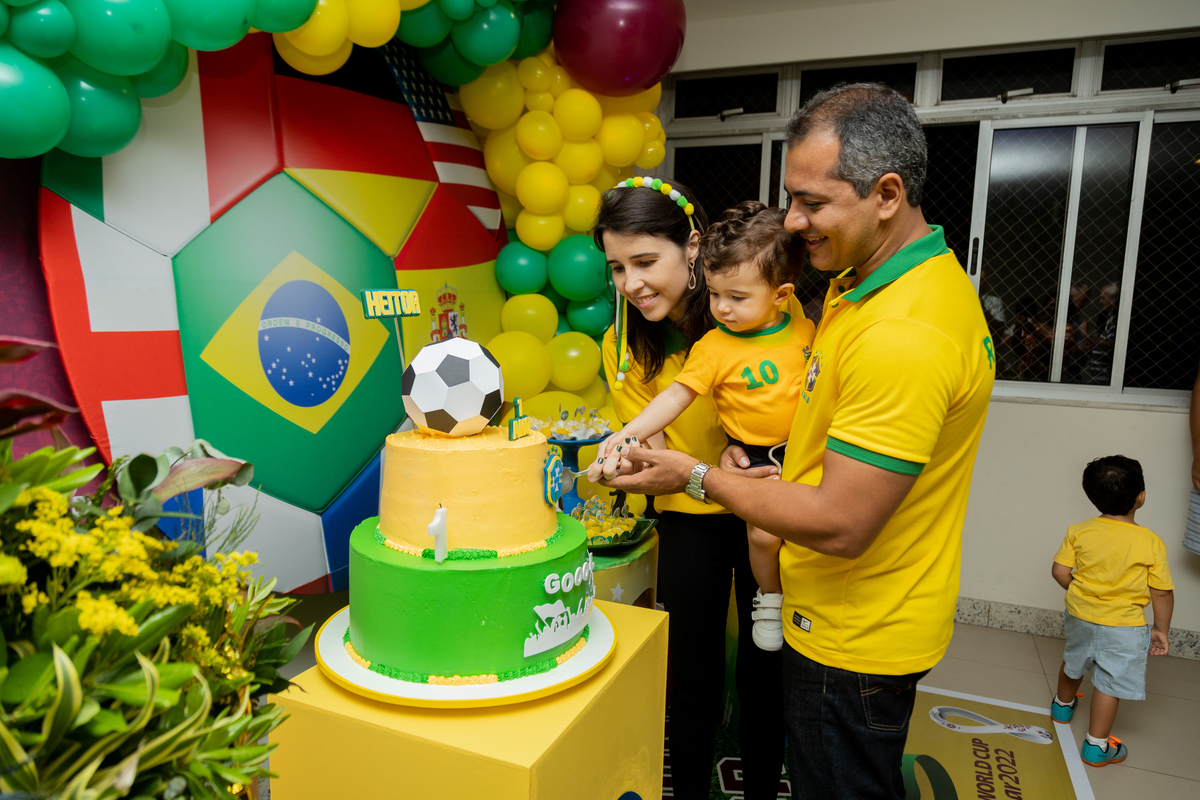 aniversariante com seus pais cortando o bolo