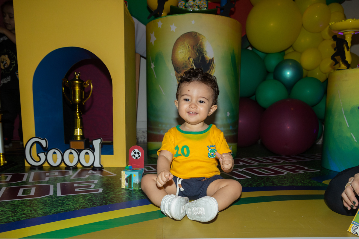 aniversariante sorridente sentado no chão com cenário copa do mundo