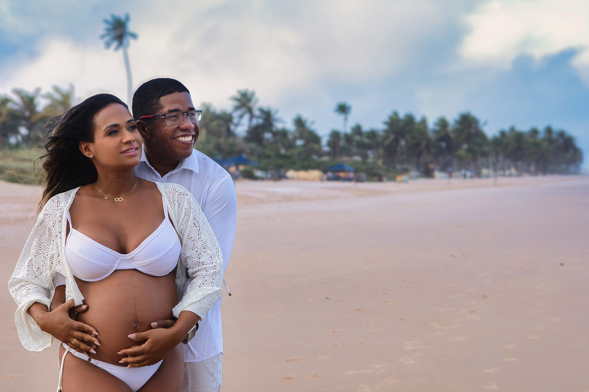 gestante e papai abraçando a barriga na beira do mar