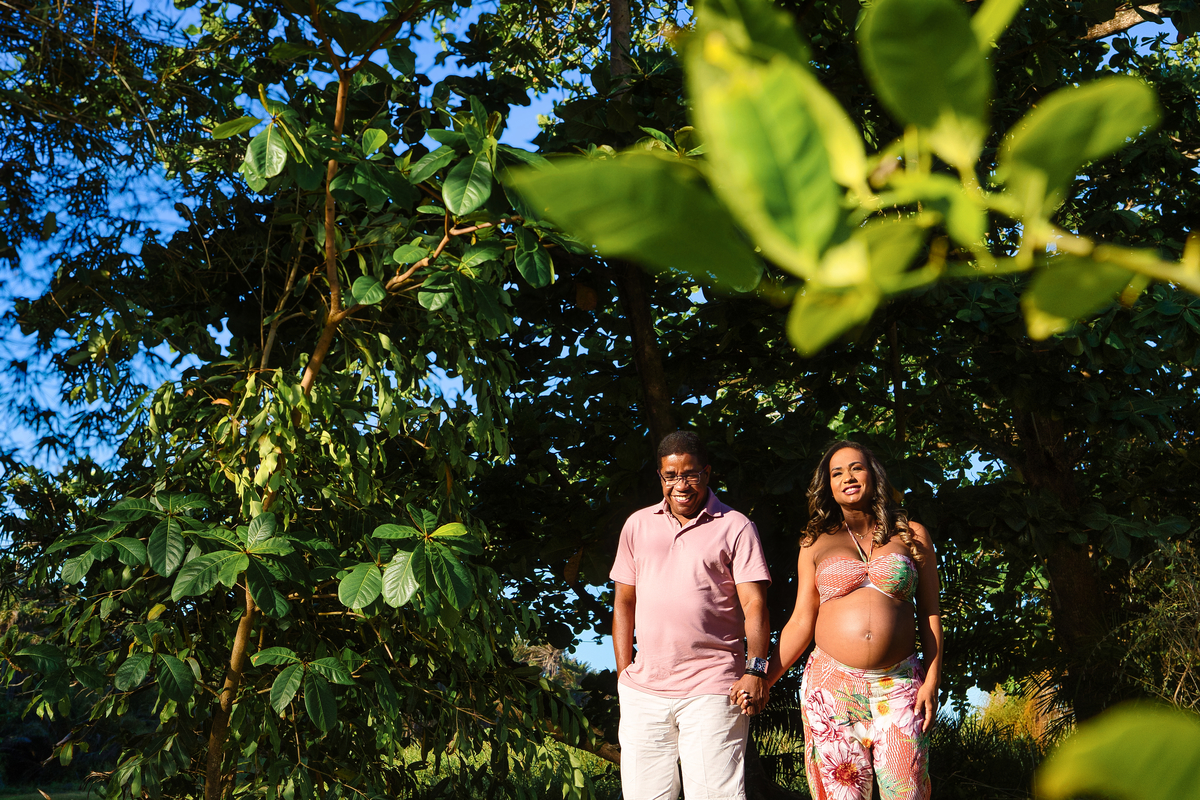 gestante e papai de mãos dadas entre as árvores