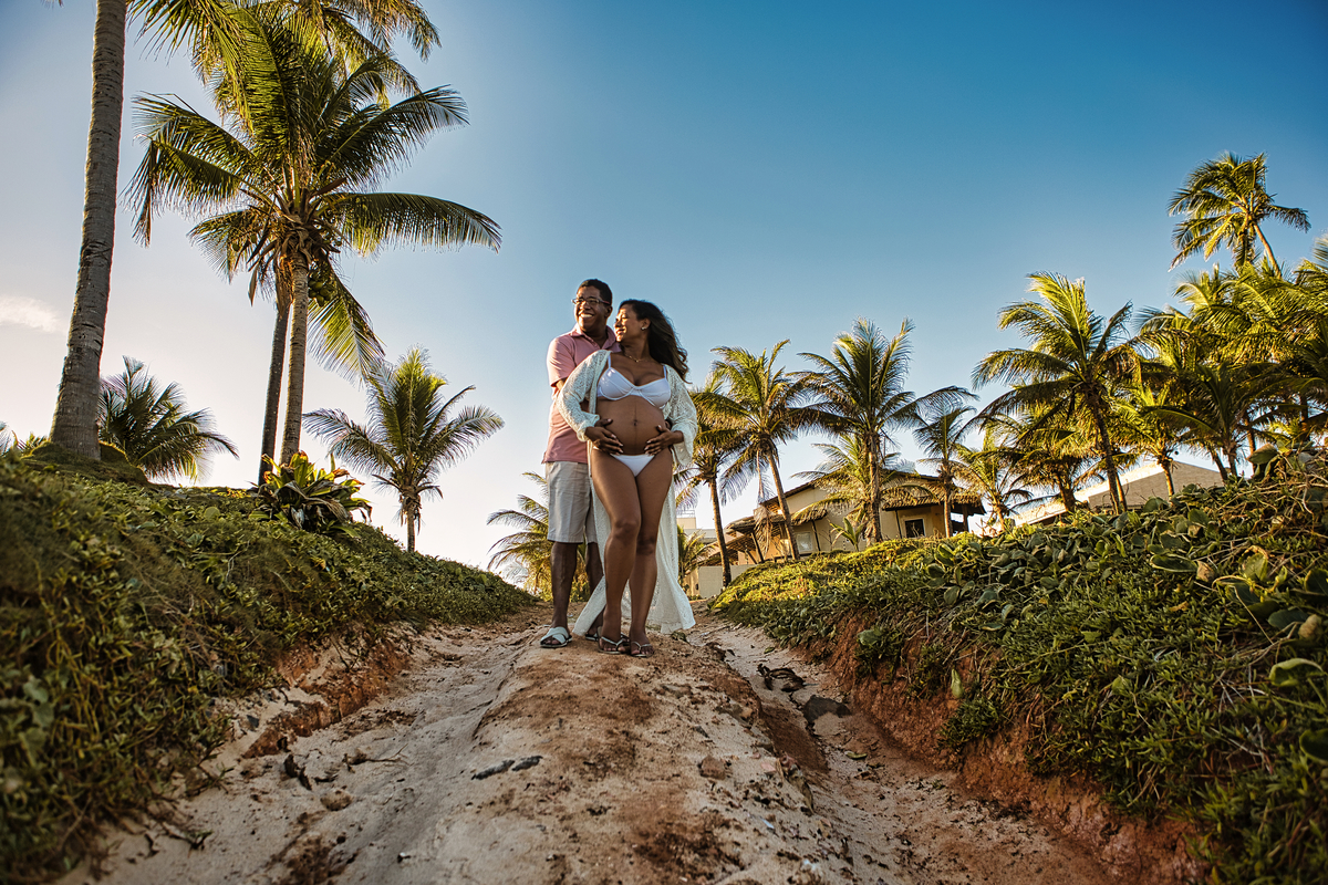 gestante e papai abraçando a barriga entre coqueiros