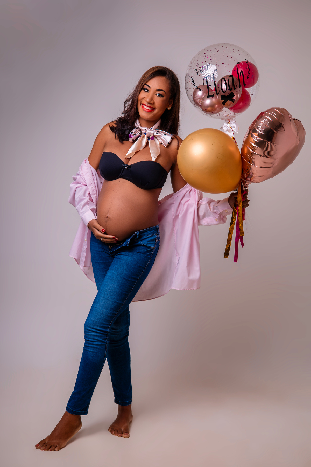 gestante segurando balões e tocando na barriga